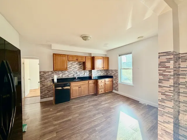 a large kitchen with kitchen island granite countertop a refrigerator and wooden cabinets