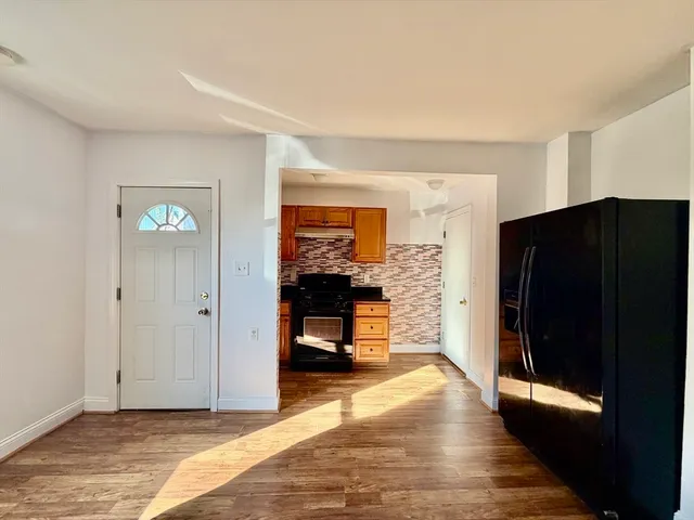 a view of an empty room with wooden floor and a cabinet