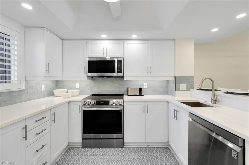 1672 Spoonbill Lane, Unit B Naples, FL 34105 - Photo 5 of 41 a kitchen with white cabinets and stainless steel appliances