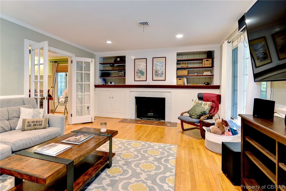 122 Selden Road Newport News, VA 23606 - Photo 5 of 38 Hardwood floored living room featuring built ins, a wood-burning fireplace, and crown molding