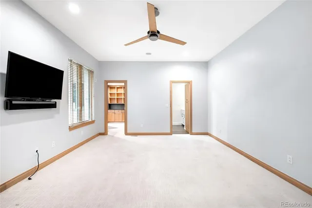 an empty room with windows and a ceiling fan