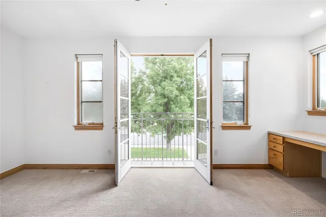 an empty room with a window and chandelier fan