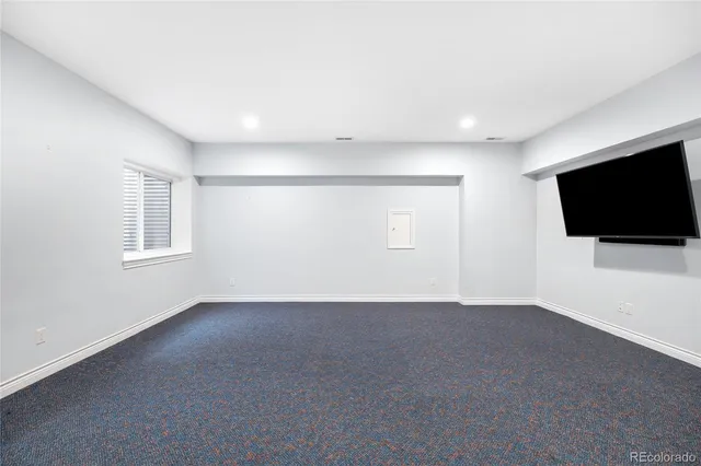 a view of an empty room with wooden floor and a flat screen tv