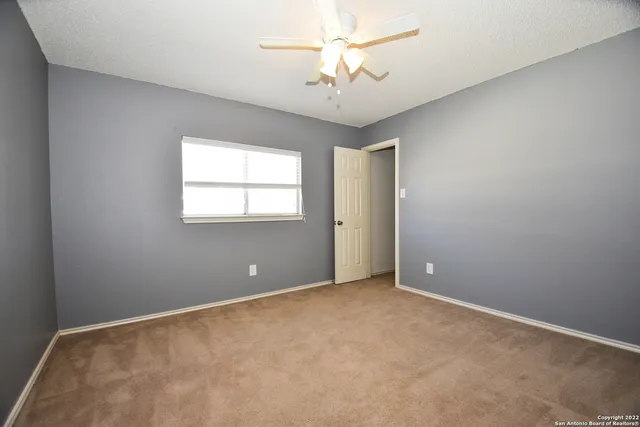 an empty room with windows and fan