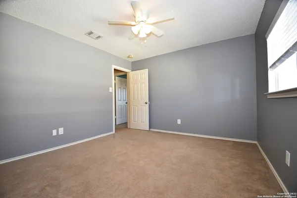 an empty room with windows and fan