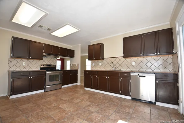 a large kitchen with granite countertop a refrigerator stove top oven a sink and dishwasher