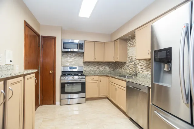 a kitchen with stainless steel appliances granite countertop a refrigerator and a stove top oven