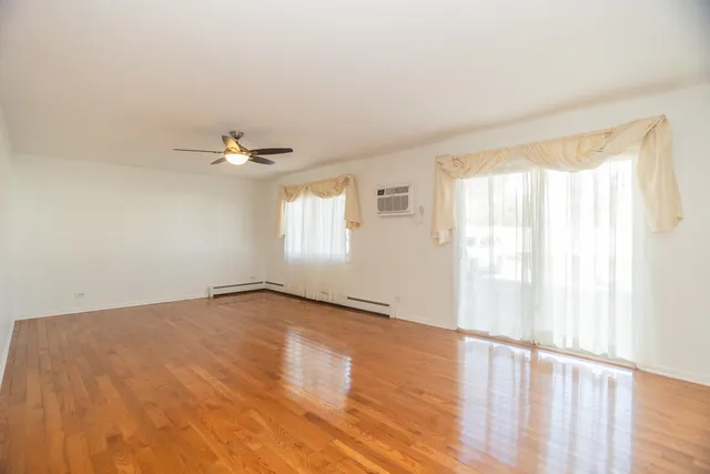 a view of an empty room with a window and wooden floor