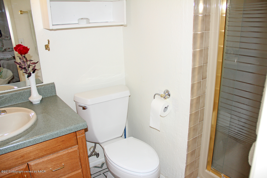 5324 Allen Street Amarillo, TX 79110 - Photo 14 of 24 a white toilet sitting next to a bathroom sink and a mirror