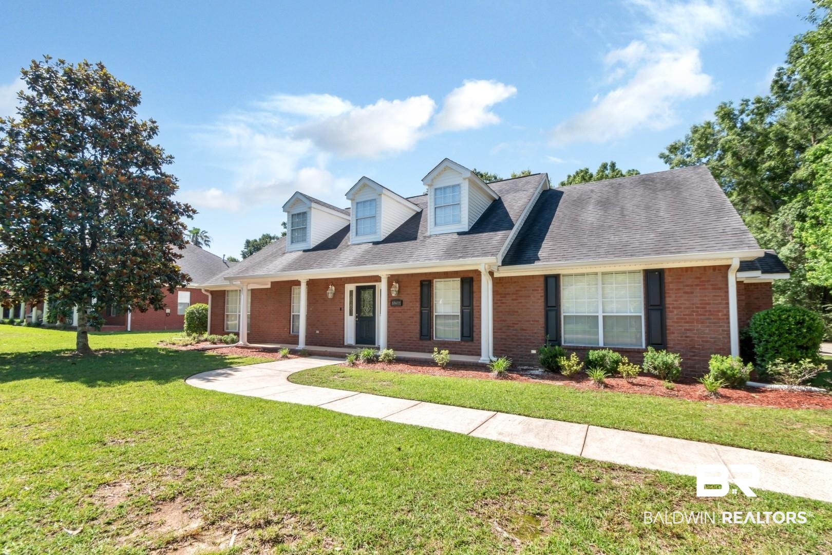 10691 Hunters Ridge Drive Mobile, AL 36695 - Photo 2 of 37 Brick exterior with a prominent entry, featuring a covered porch with white columns, a dark front door, and symmetrical dormer windows