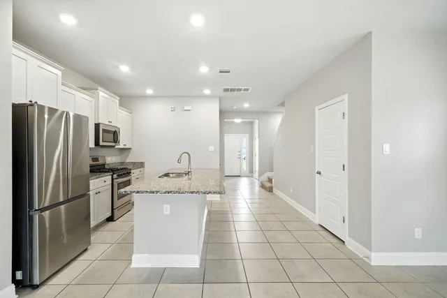 a large kitchen with a large counter top stainless steel appliances and cabinets