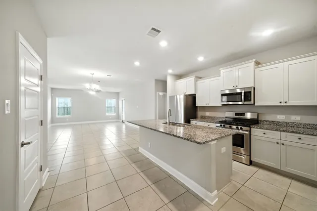 a large kitchen with stainless steel appliances granite countertop a stove a sink and a refrigerator