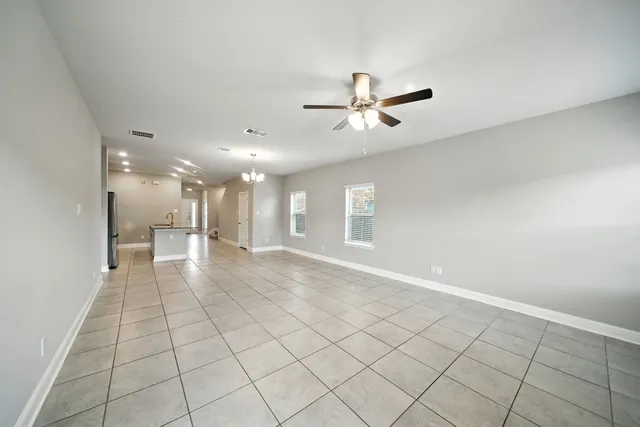 a view of an empty room and a chandelier fan