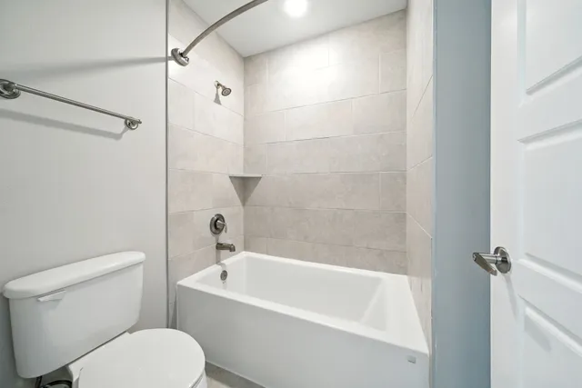 a white toilet sitting next to a bath tub