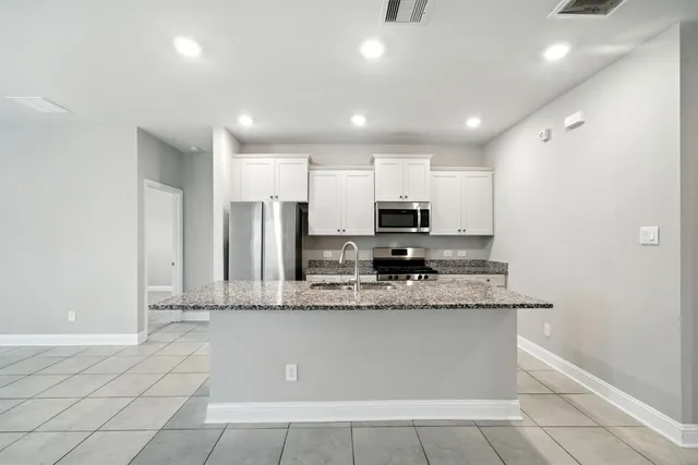 a large kitchen with stainless steel appliances kitchen island granite countertop a sink a stove a microwave a counter top and cabinets