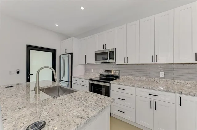 a kitchen with stainless steel appliances granite countertop a sink a stove and cabinets