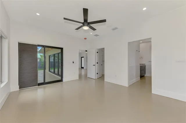 an empty room with a ceiling fan and windows