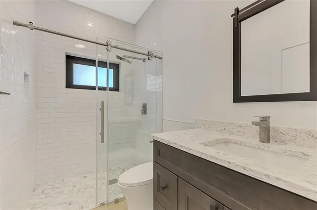 a bathroom with a sink a toilet a shower and a mirror