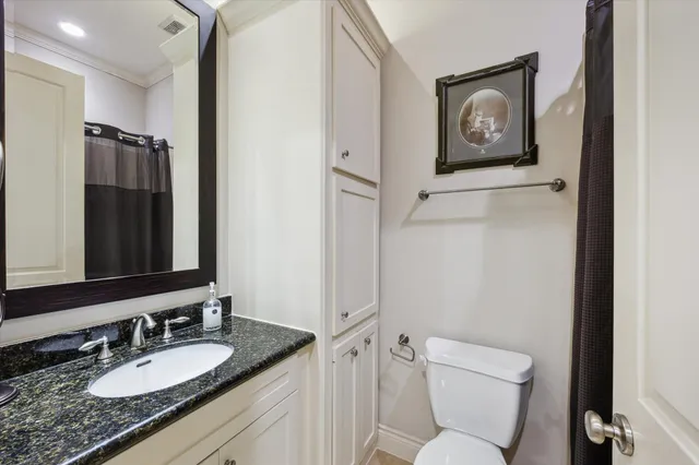 a bathroom with a granite countertop toilet sink and mirror