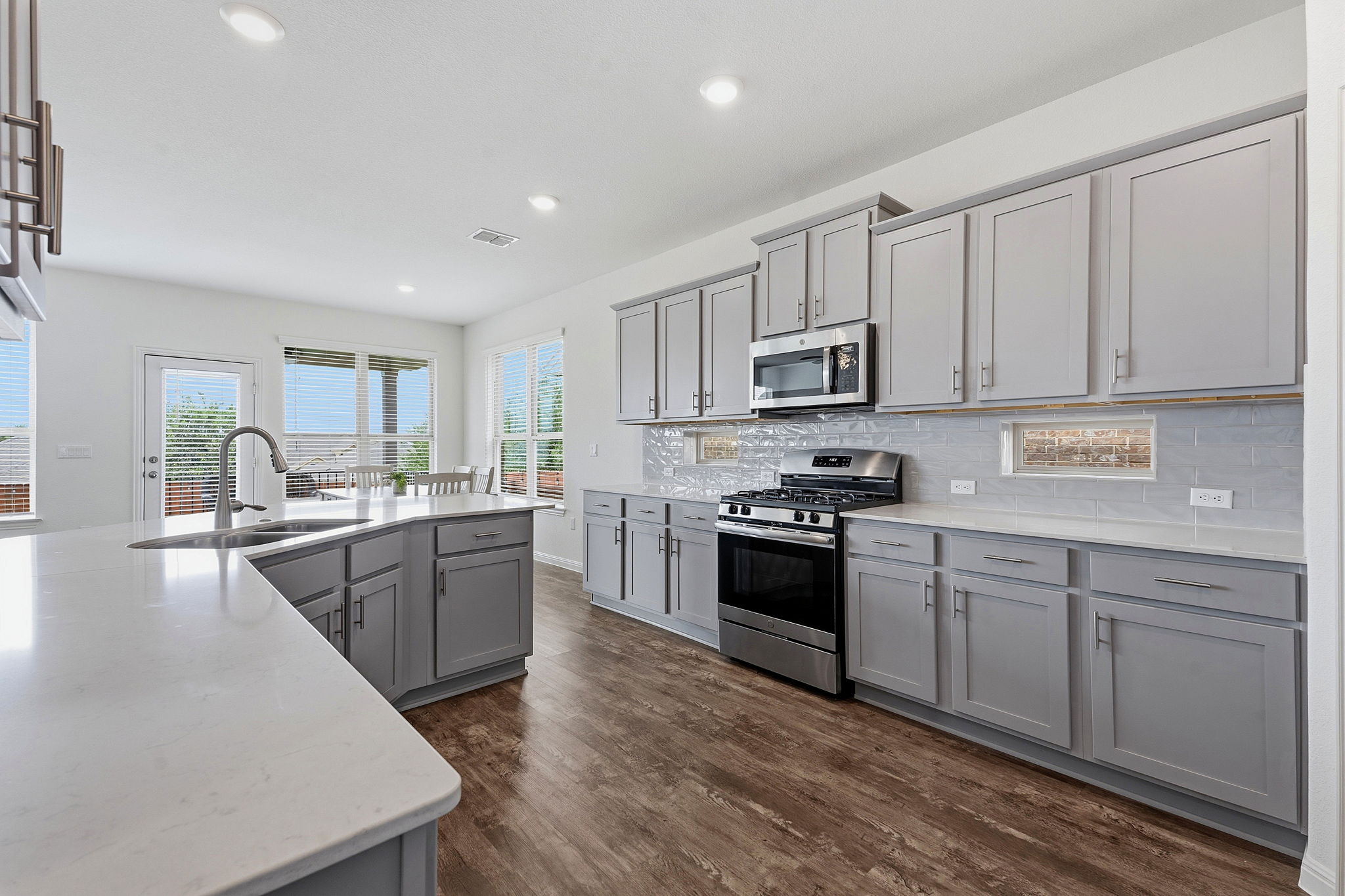 609 Allende Bend, Unit 130 Austin, TX 78748 - Photo 9 of 33 a kitchen with stainless steel appliances granite countertop a stove top oven a sink dishwasher and a refrigerator with wooden floor
