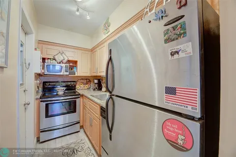 a kitchen with stainless steel appliances granite countertop a sink a refrigerator and wooden cabinets