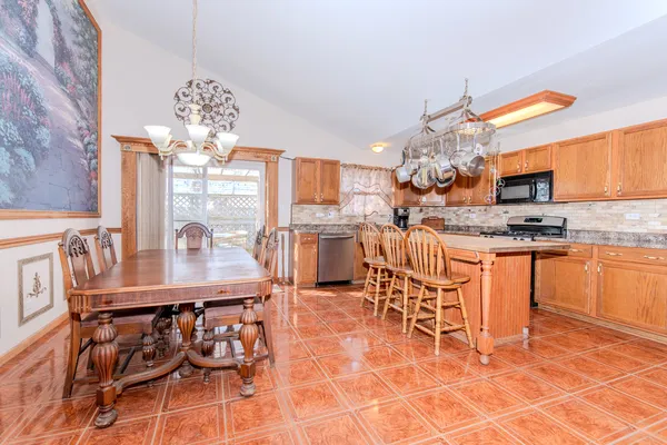a kitchen with stainless steel appliances granite countertop a stove top oven a dining table and chairs with the cabinets