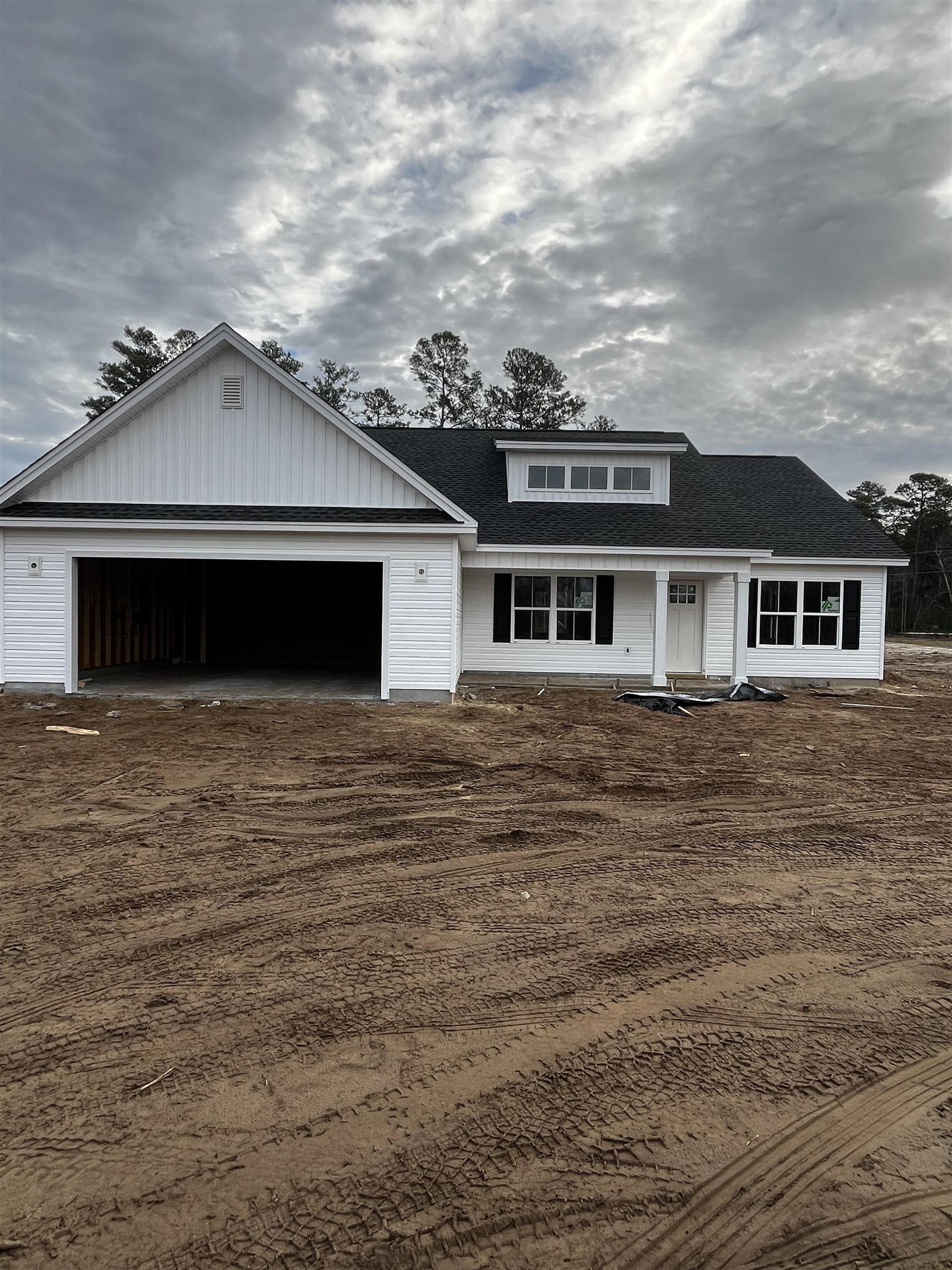 View of front of house with roof with shingles, a porch, and an attached garage