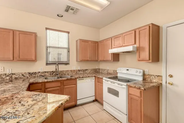 a kitchen with granite countertop a sink stove and cabinets