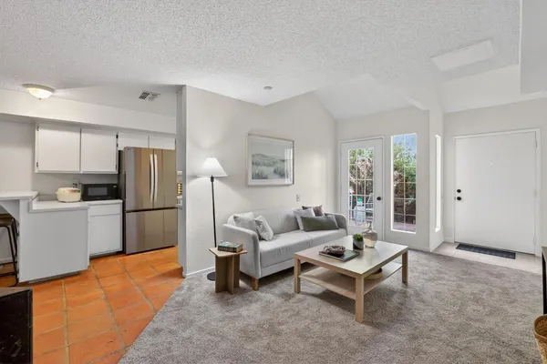 a living room with furniture a large window with kitchen view