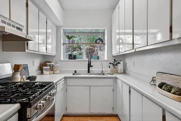 a kitchen with granite countertop a sink stove and cabinets