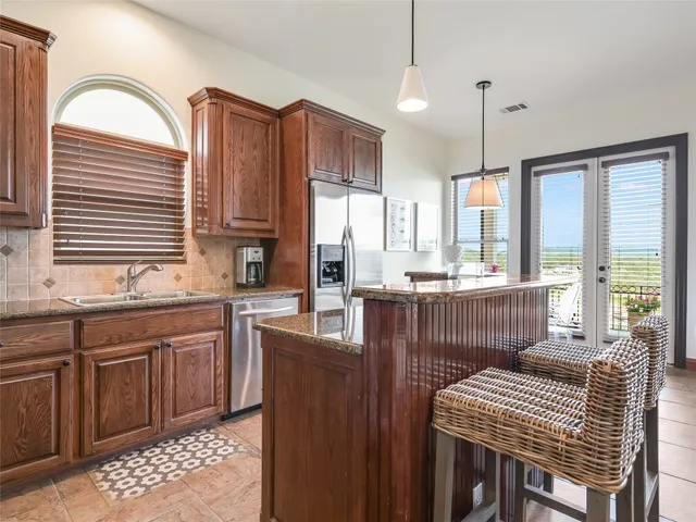 a kitchen with stainless steel appliances granite countertop a stove a sink dishwasher a dining table and chairs with wooden floor