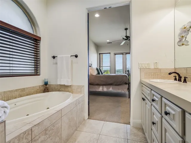 a spacious bathroom with a tub sink and mirror