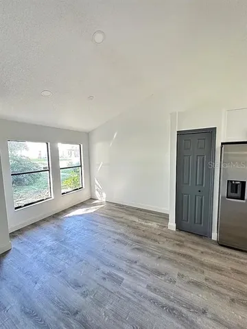 an empty room with wooden floor and windows