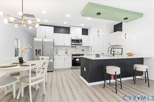 a kitchen with stainless steel appliances kitchen island granite countertop a table chairs and a refrigerator
