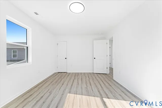 an empty room with wooden floor and windows