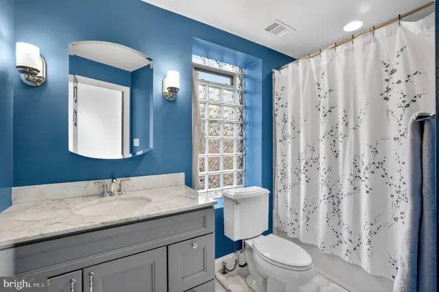 a bathroom with a granite countertop sink toilet a mirror and shower