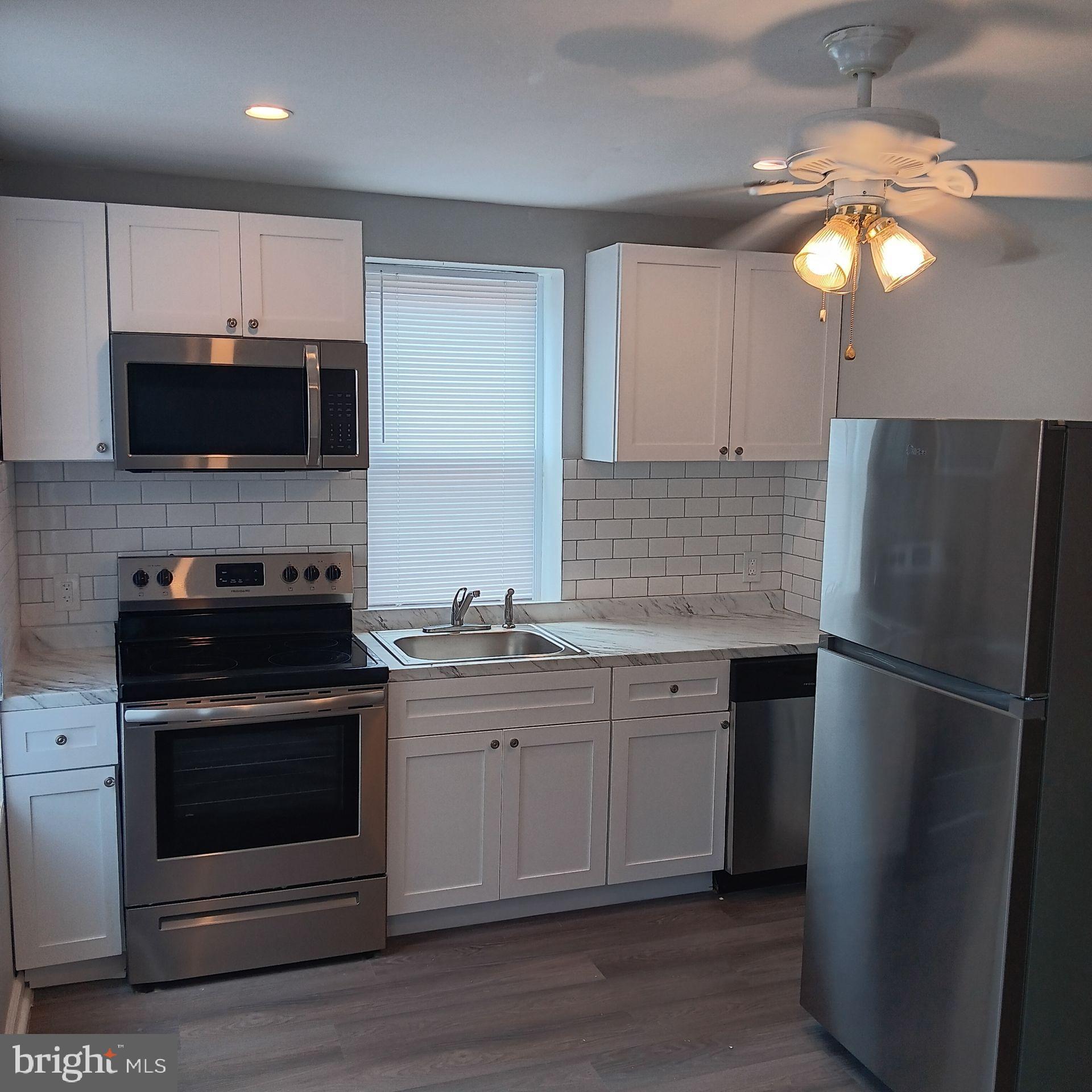 2036 North Gratz Street, Unit 2 Philadelphia, PA 19121 - Photo 4 of 14 a kitchen with a sink a microwave a refrigerator and cabinets