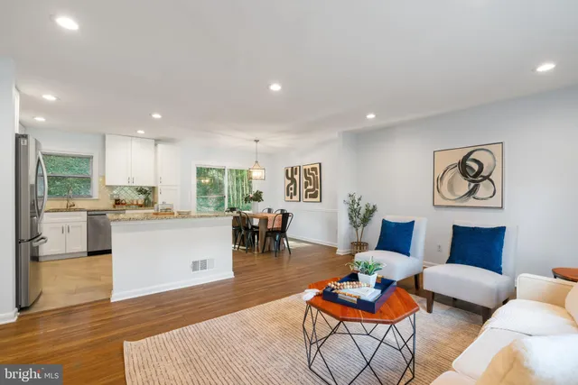 a living room with furniture and kitchen view with wooden floor