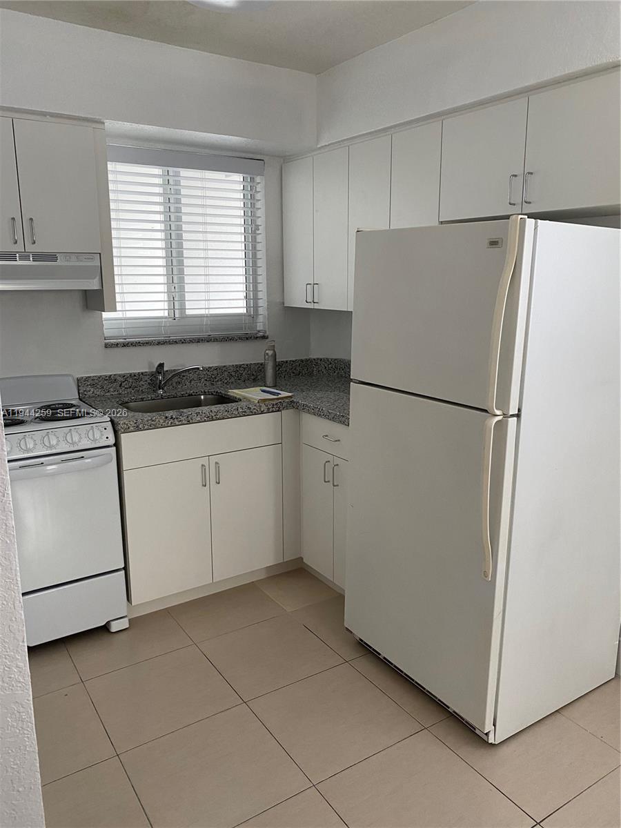 35 Southwest 21st Avenue, Unit 4 Miami, FL 33135 - Photo 5 of 8 a white refrigerator freezer sitting in a kitchen with white cabinets