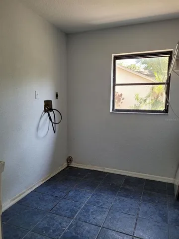an empty room with wooden floor windows and chandelier