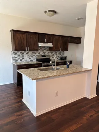 a kitchen with stainless steel appliances granite countertop a sink stove and wooden floor