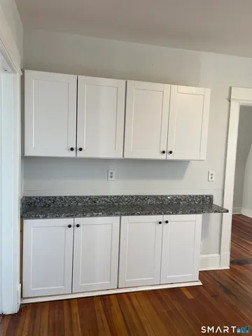a kitchen with granite countertop white cabinets and a wooden floor