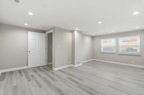 a view of an empty room with wooden floor and window