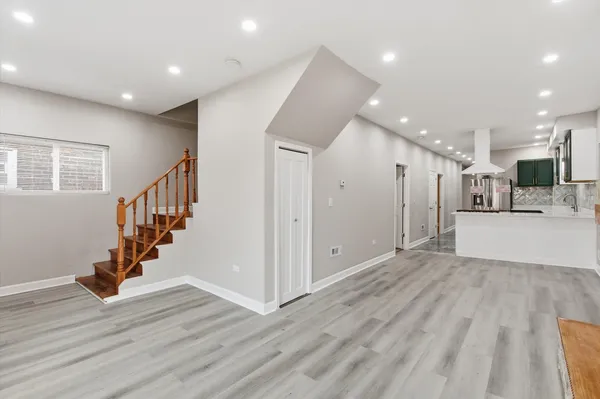 a view of an empty room with wooden floor and stairs