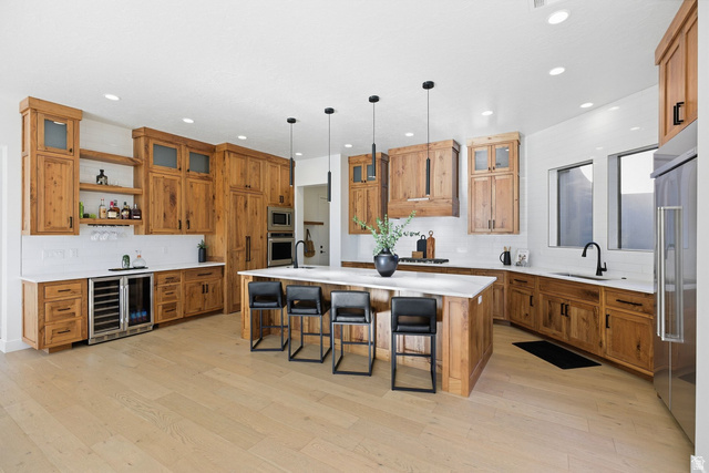 2197 Reserve Circle St. George, UT 84770 - Photo 6 of 57 Kitchen with a spacious island, wood finish cabinets, a kitchen bar, open shelves, and beverage cooler