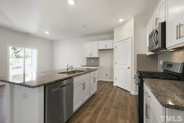 a kitchen with granite countertop a sink stove and refrigerator
