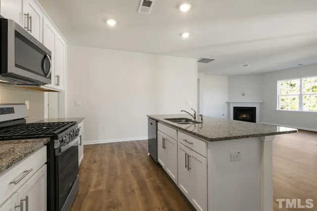 a kitchen with granite countertop a sink a counter top space appliances and cabinets