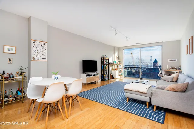 a living room with furniture a flat screen tv and a dining table with wooden floor
