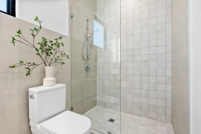 a white toilet sitting next to a shower