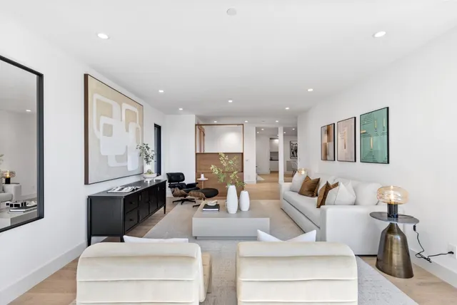 a living room with furniture a large window and wall paintings